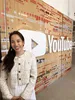 Asian female standing in front of a large YouTube logo displayed on the wall