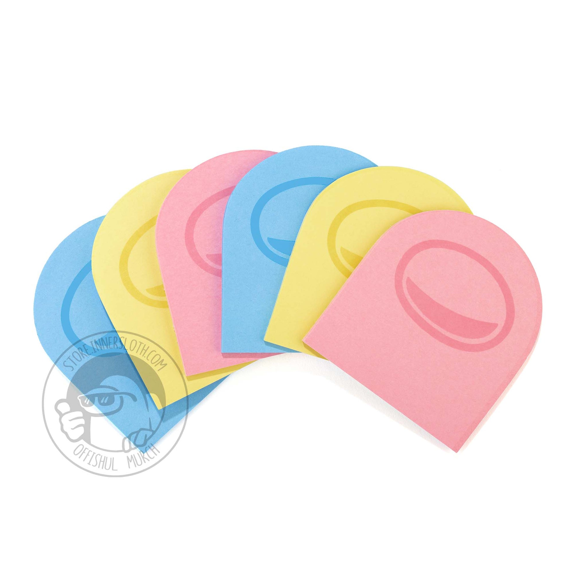 A product photo of six packs of Post-It notes, shaped like crewmate heads. Two of each of the Post-It colors are shown: blue, yellow, and pink. A faded visor design are printed on all the Post-Its. The Post-It notes are spread across a surface in an arc like a deck of cards.