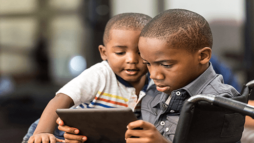 Αφροαμερικανό αγόρι που παίζει σε tablet με τον μικρότερο αδερφό του