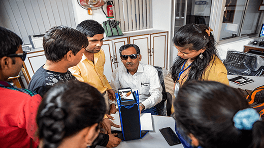 Een docent laat zien hoe u ondersteunende technologie kunt gebruiken om braille te lezen in een beroepscentrum voor blinden in India. 