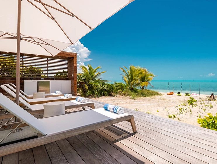 a deck with chairs and umbrellas on a beach