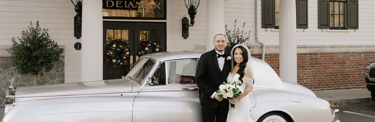 a man and woman posing in front of a white car