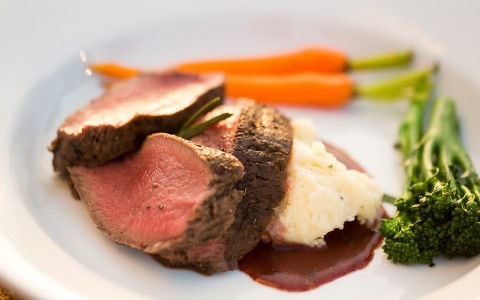 slices of steak on top of mashed potatoes