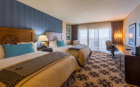 double beds in a hotel room with a carpet and large balcony