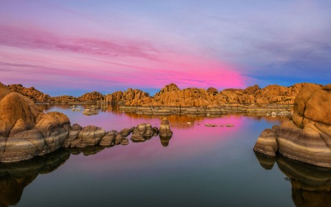 lake with rocky mountains and pink sky