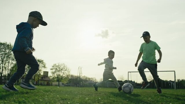 Kids playing soccer on the grass. Boys train in a game of football, happy children who score a goal.