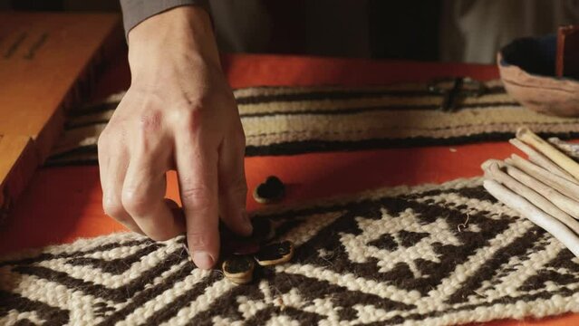 Traditional mapuche recreational games. Closeup view of a man playing Auarr-cuden mapuche game, similar to payana. He throws sliced beans.