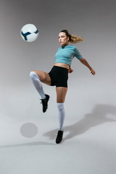 Active woman kicking ball in studio