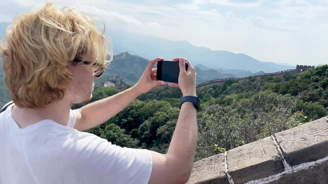 Young man traveling and using smartphone for video and photos