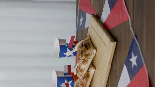 Fiestas Patrias Chile putting up a terremoto glass Empanada and chilean flags vertical