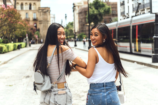 Two Chinese girls holding hands smiling