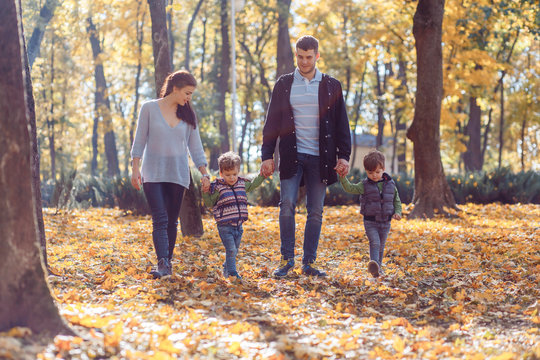 Natural pictures of a happy family of four having fun outsiade on a sunny autumn day. Togetherness and happiness concept