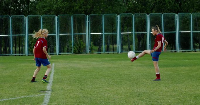 Young Caucasian teenager girl soccer football players heading the ball during practice session. 4K UHD