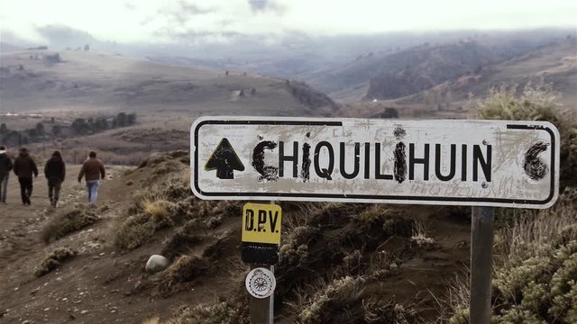 People Walking in a Dirt Road near a Road Sign in Patagonia Argentina, South America. Slow Motion Shot. 