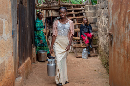 Three young african women carrying milk containers 