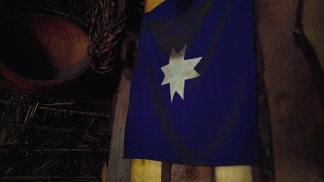 Handheld of a blue Guñelve Mapuche flag hanging from the interior wall of a Ruka traditional aboriginal house, Chile