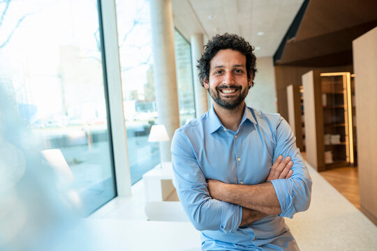 Happy man with arms crossed in library