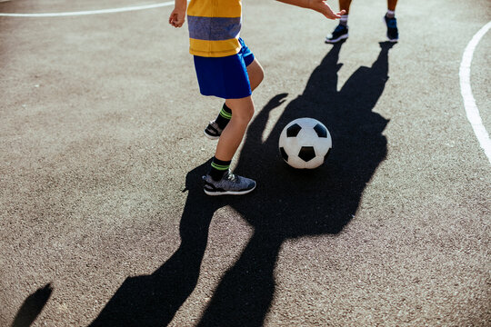 Father and son playing football outdoors at the local court