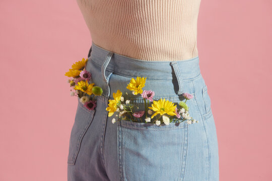 Woman posing with gerberas flowers in jeans pocket