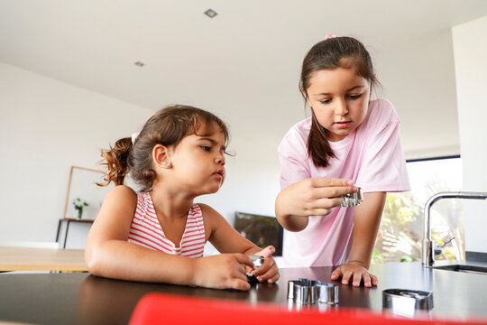 Two young girls baking cookies in a modern kitchen