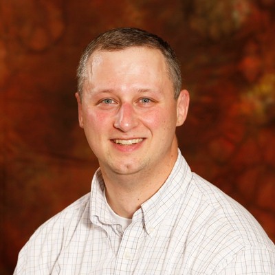 Headshot of Joe Petroske, a white man with brown hair and blue eyes, wearing a white shirt