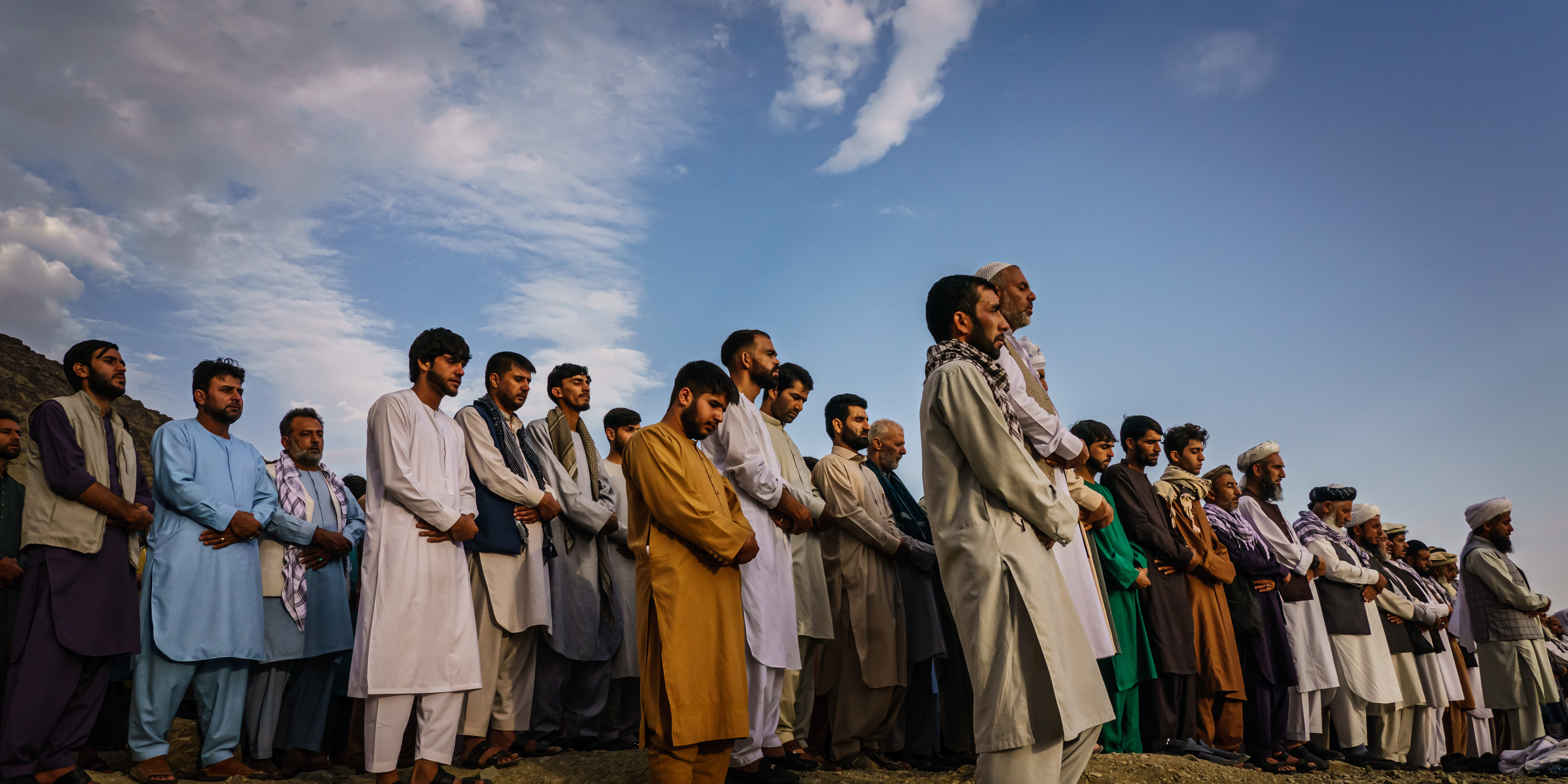 KABUL, AFGHANISTAN -- AUGUST 30, 2021: Islamic prayers are recited for the dead before they could be laid into the ground to be buried, as around 200 people attend a mass funeral for the 10 people the family said to have been killed in a U.S. drone strike, in Kabul, Afghanistan, Monday, Aug. 30, 2021. (MARCUS YAM / LOS ANGELES TIMES)