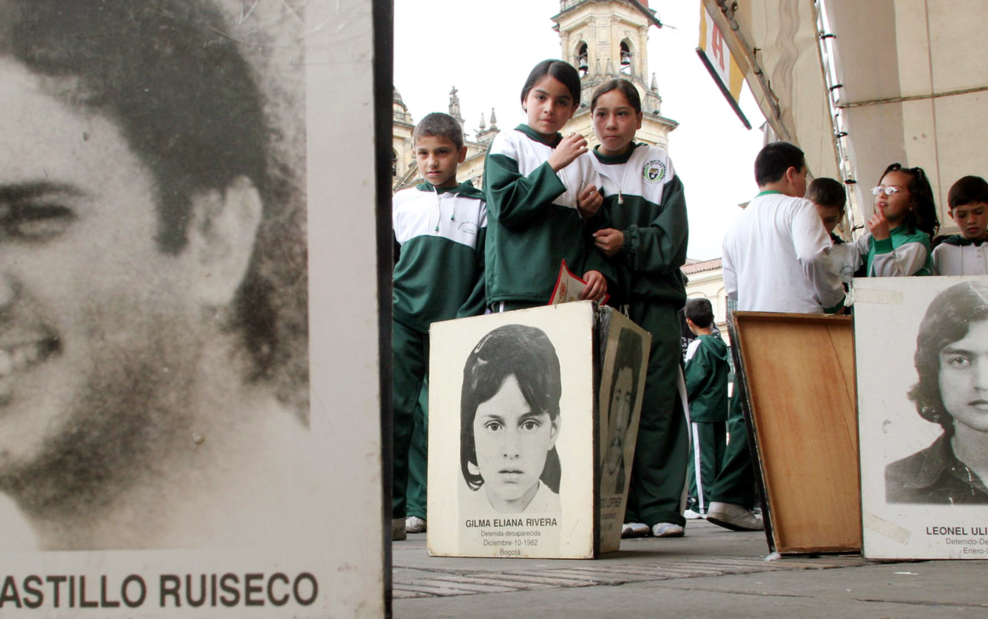 School children look at photos of the disappeared and killed that form part of an outdoor gallery of victims of paramilitary violence in Bogota, Colombia's main square, April 7, 2005. The Colombian Congress is currently debating a bill to grant leniency to paramilitary warlords who lay down their arms.(AP Photo/Fernando Vergara) **EFE OUT**