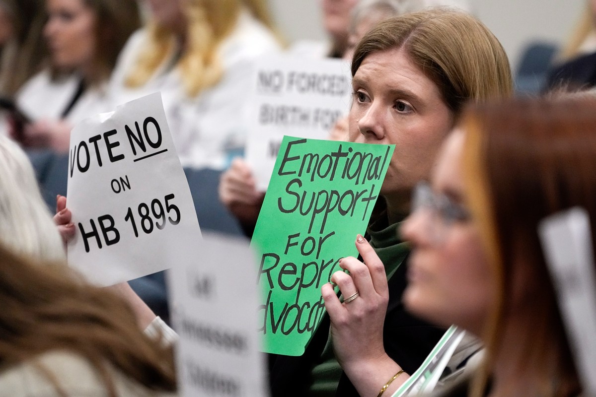 Kay Cook holds signs during a House Health Committee meeting against HB1895, Wednesday, Feb. 21, 2024, in Nashville, Tenn. The bill would create the criminal offense of abortion trafficking of a minor. (AP Photo/George Walker IV)