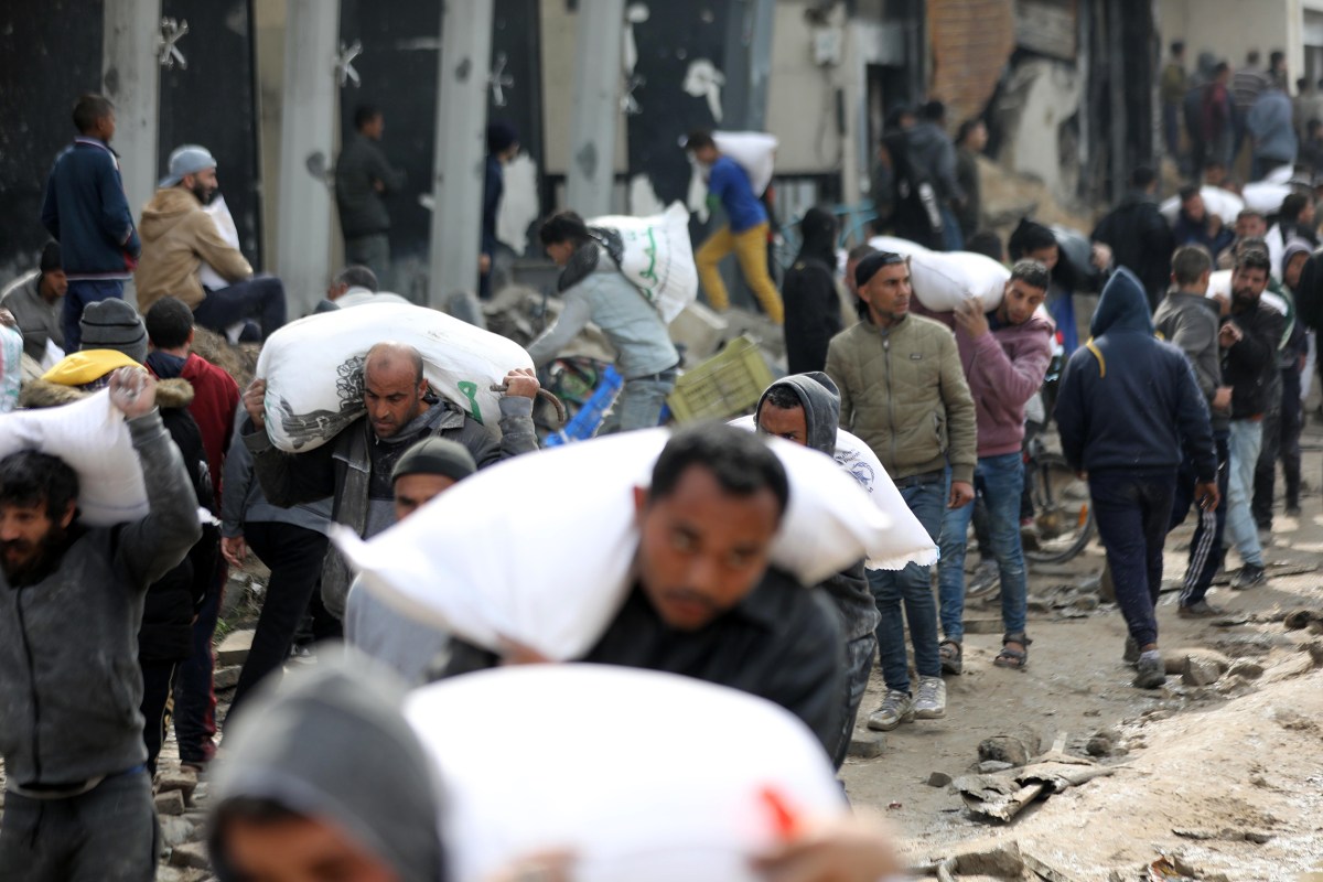 GAZA CITY, GAZA - FEBRUARY 19: Palestinians receive bags of flour as they wait for aid supplies carried by trucks to enter from the border in Gaza Strip on February 19, 2024. The Israeli war on Gaza has pushed 85% of the territory's population into internal displacement amid acute shortages of food, clean water, and medicine, while 60% of the enclave's infrastructure has been damaged or destroyed, according to the UN. (Photo by Dawoud Abo Alkas/Anadolu via Getty Images)