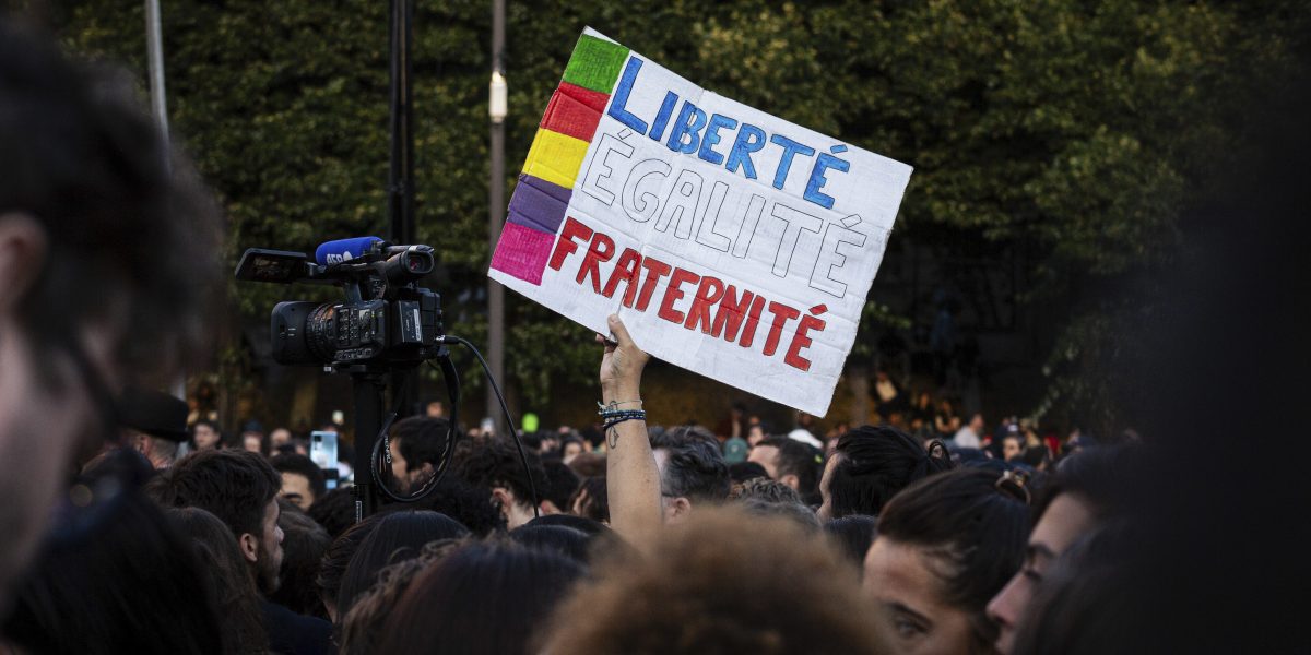 A sign that says "Freedom, Equality and Fraternity" seen amidst the crowd at Place de Stalingrad, following the French legislative elections results.