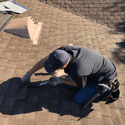 a man kneeling on a shingle roof