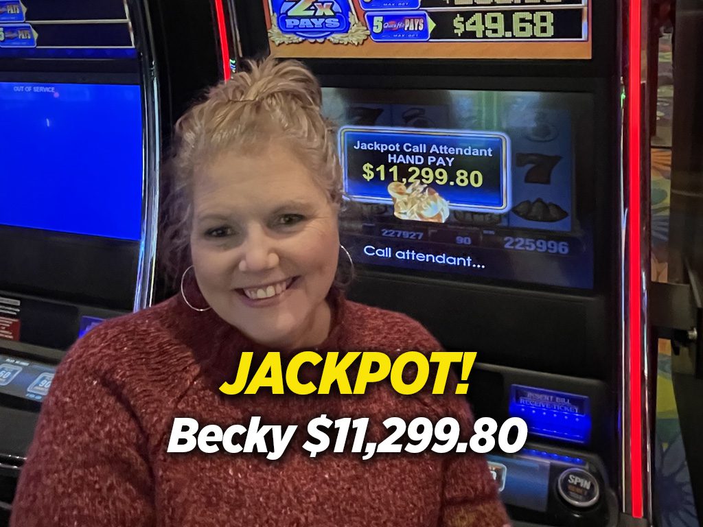 A woman smiles in front of a slot machine.