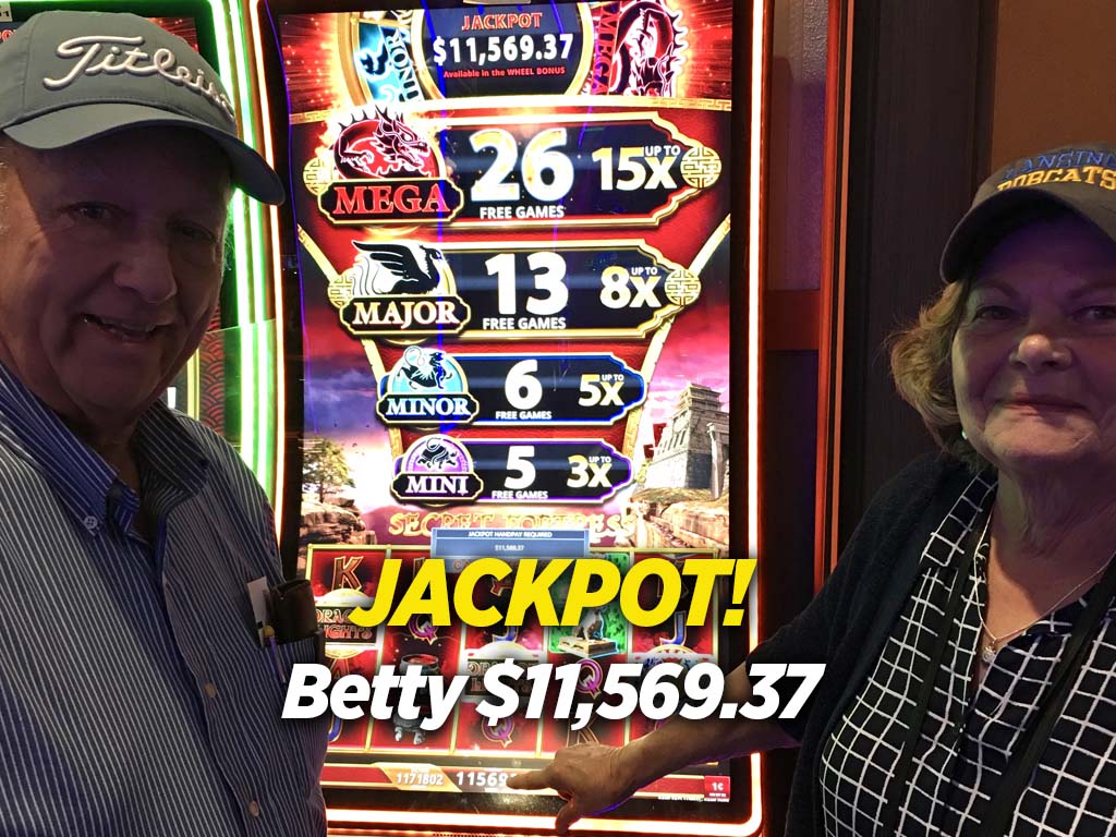 A couple of people standing in front of a slot machine.