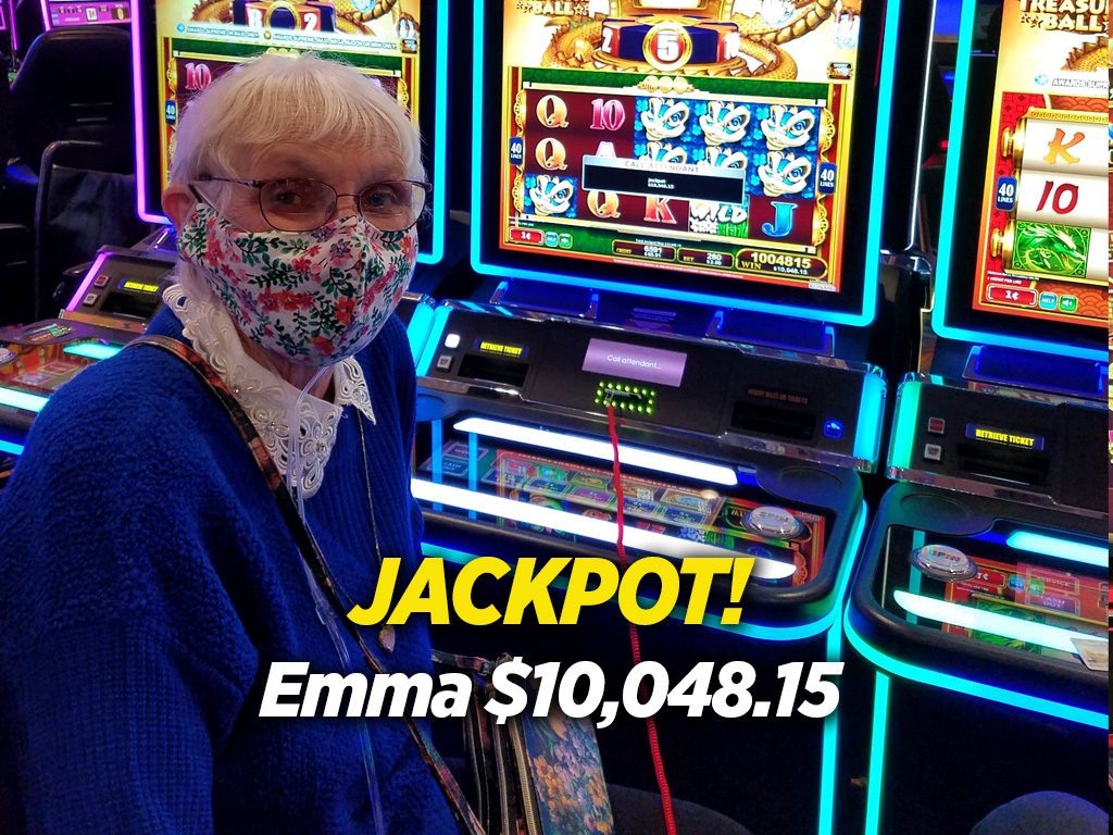 A woman in blue jacket standing next to slot machines.