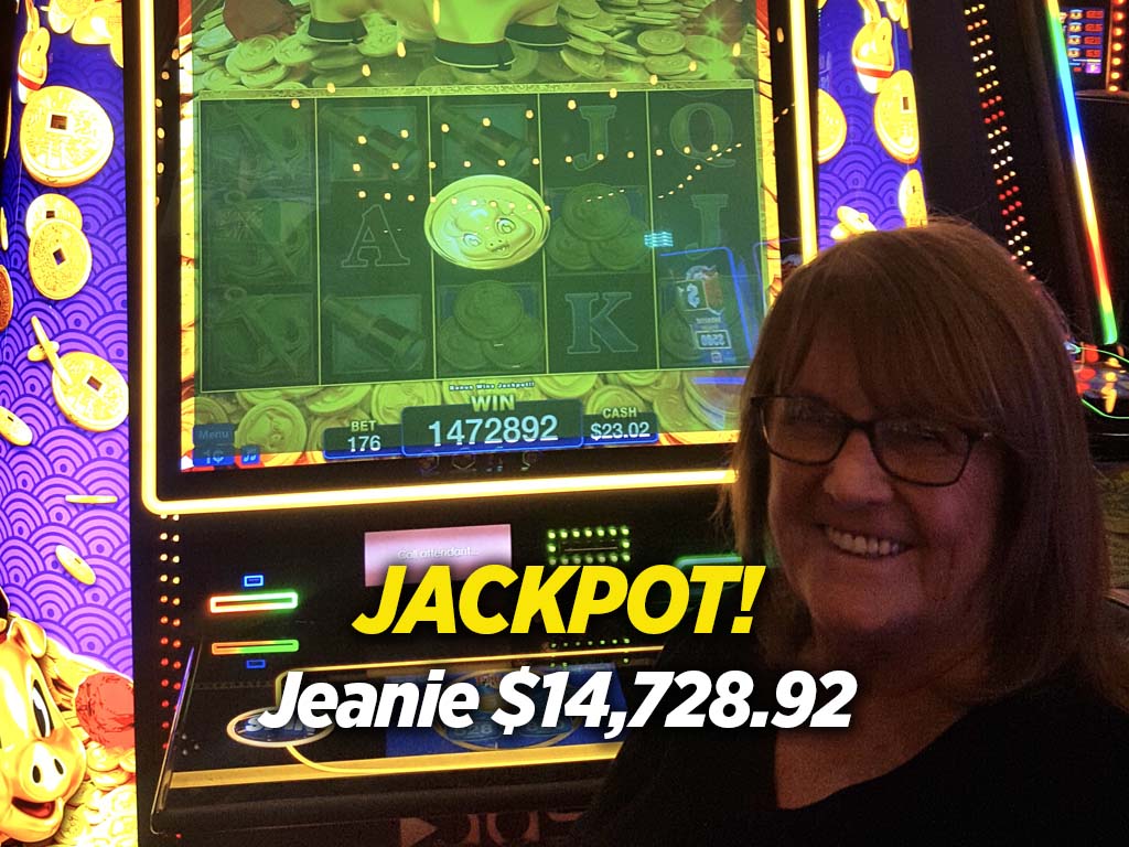 A woman is smiling in front of a slot machine.