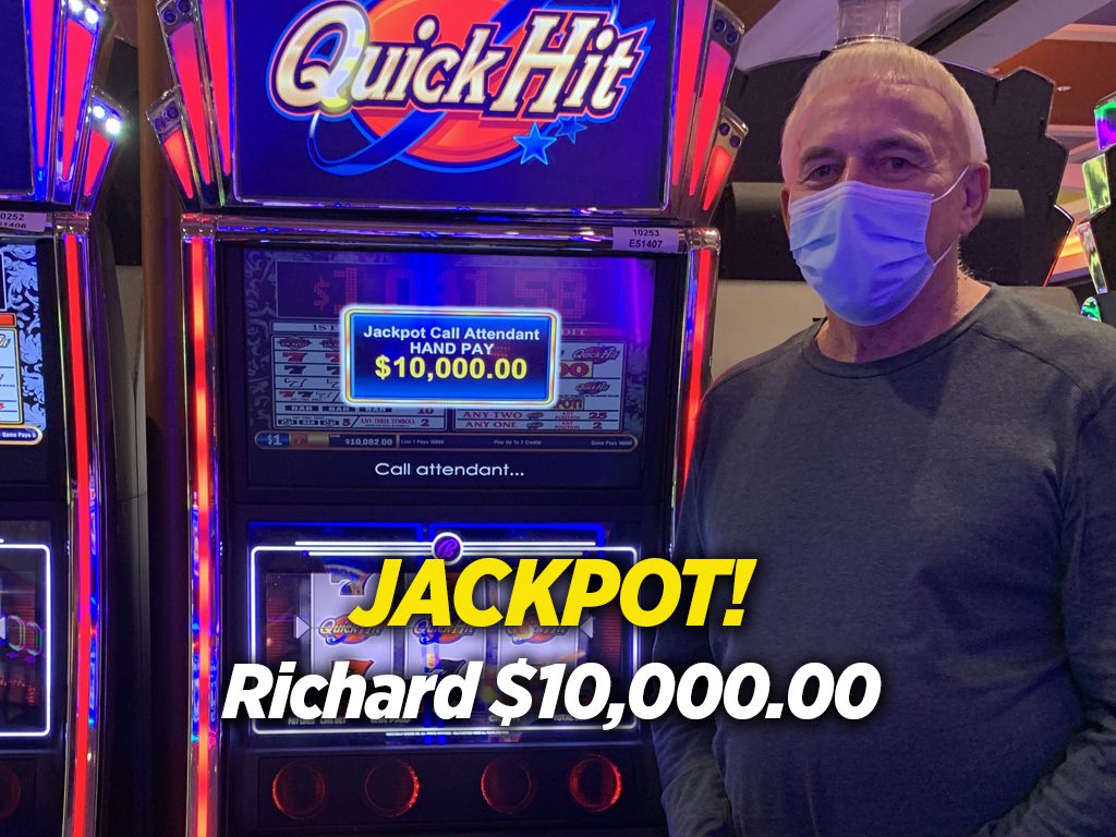 A man standing next to an old style slot machine.