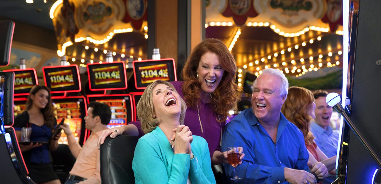 Three people laughing and drinking at a casino.