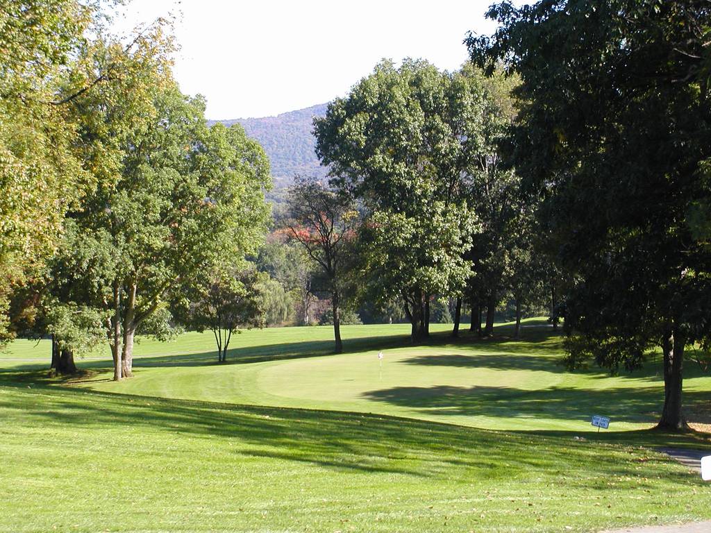 A golf course with trees and grass in the foreground.