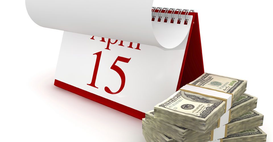 A calendar with the date of april 1 5 next to a stack of money.