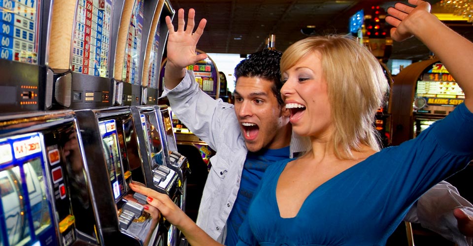 A man and woman are playing the slot machine.