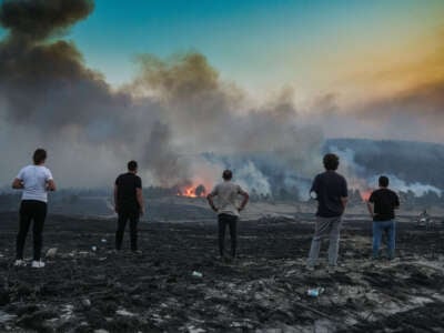 People watch the flames as firefighters respond to wildfires in Ankara, Turkiye, on August 21, 2024.