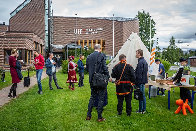 Gruppe mennesker står spredt rundt på plenen utenfor campus Alta