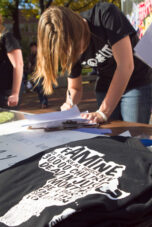 A student writes a letter to Michigan Governor Rick Snyder at the "One" Campaign tent at the Diag.