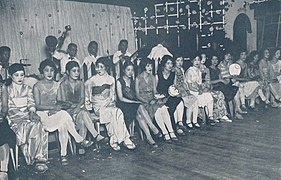 Photo d'une salle de danse : des femmes sont alignées et assises sur des chaises, prêtes à aller danser.