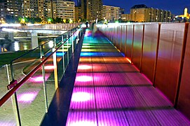 Bridge at night with multicoloured LED lights lighting the bridge from below; each successive panel is lit in a different colour.