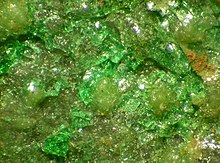 A transparent bright green mineral intermingles with a transparent yellow-green mineral.