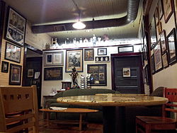 Photograph of the interior of a building; there are many framed photos on the wall as well as sculptures and other memorabilia