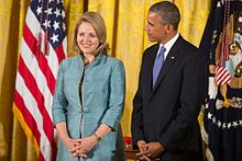 Fleming smiling, as Obama stands beside and looks to her