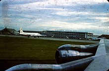 Photographie en couleur d'un aéroport pris depuis l'intérieur d'un avion situé sur la piste.