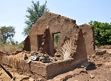 Mud walls standing in an empty area. The smooth surface is flaking off to show the interior of the walls.